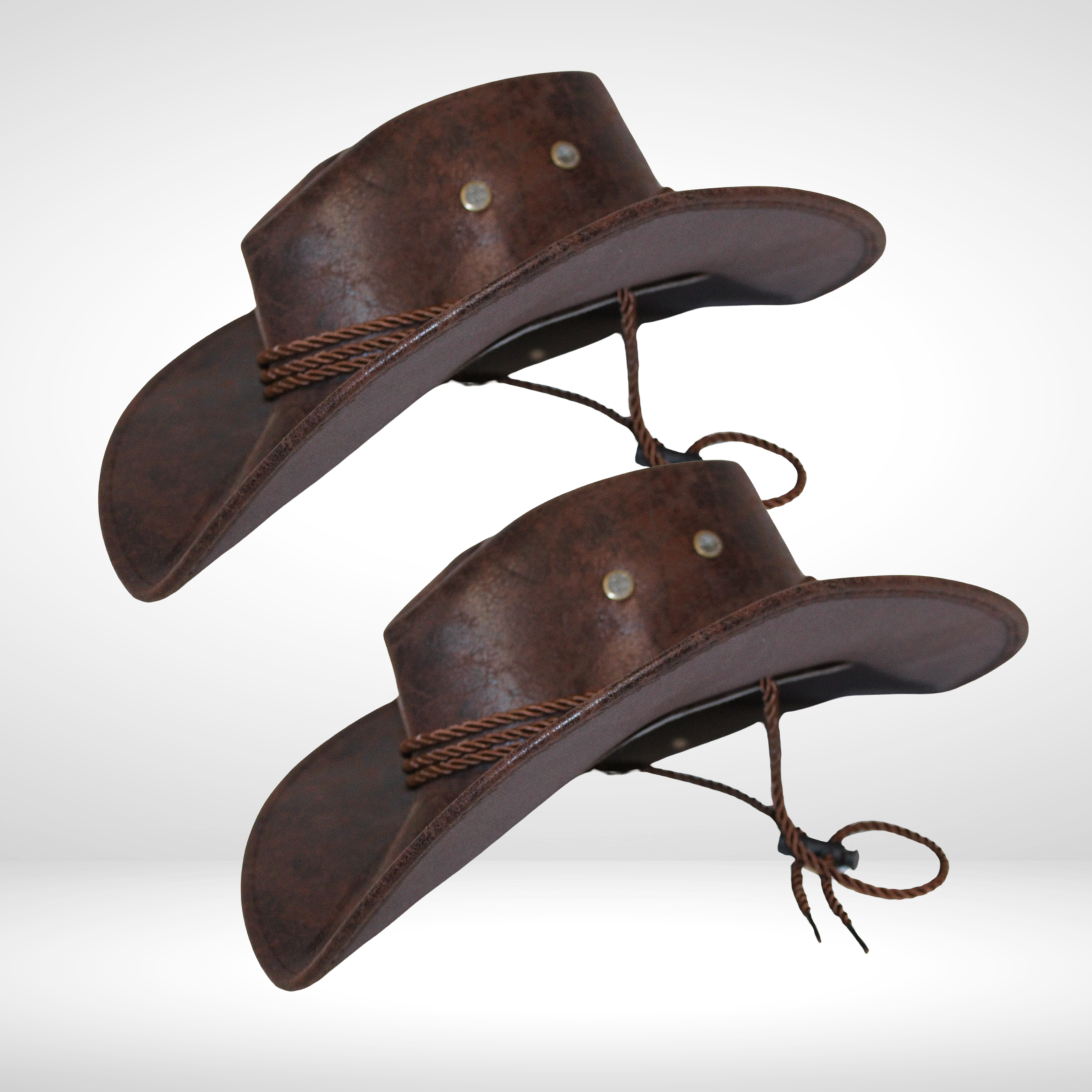 Two brown leather cowboy hats with decorative leather bands and chin straps, facing slightly downward, against a plain white background.