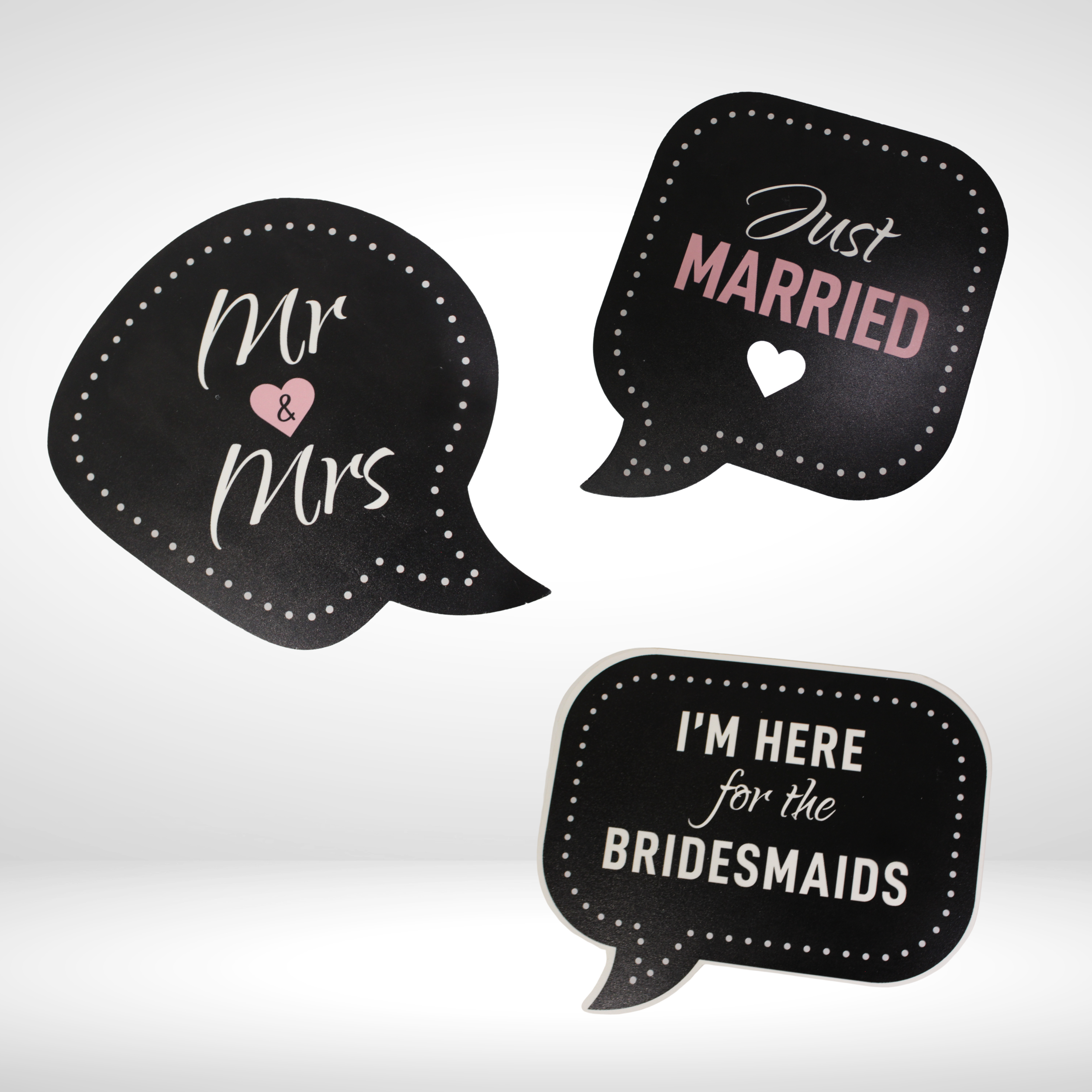 Three black speech bubble signs with white and pink text, reading 'Mr & Mrs,' 'Just Married,' and 'I'm here for the bridesmaids'.
