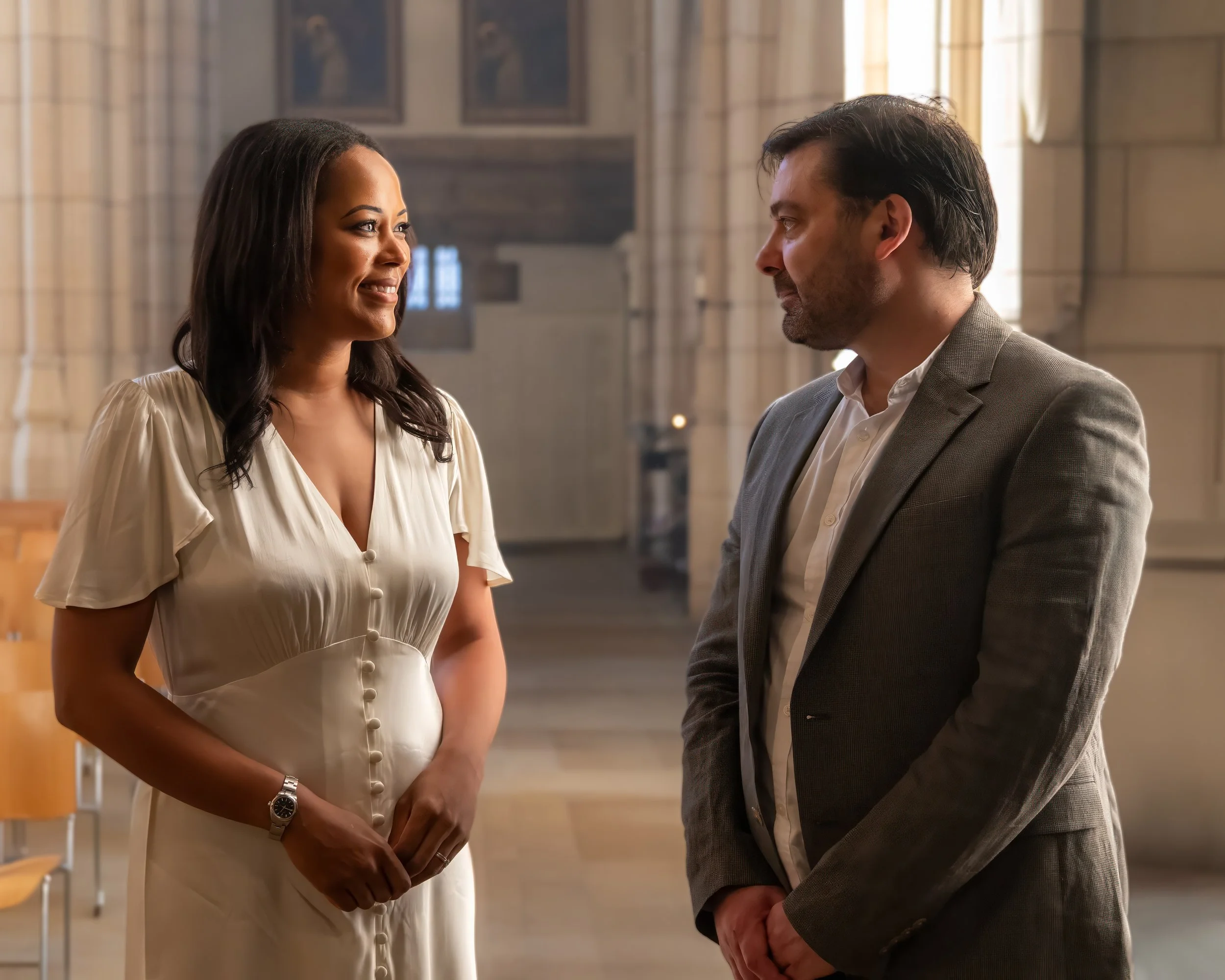 A man and woman looking lovingly at each other in a grand interior.