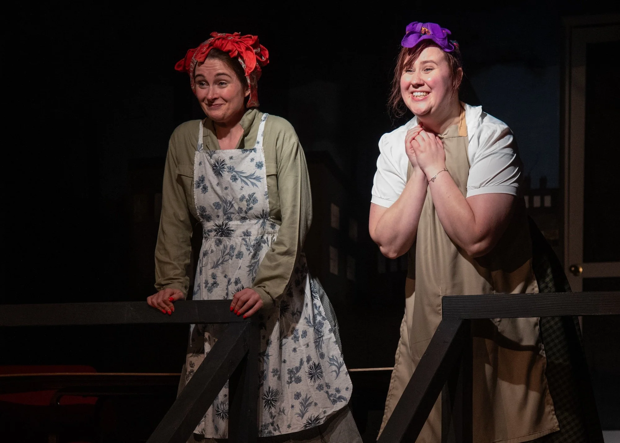 Drama scene: Two women standing on a stage, looking happily off-screen.