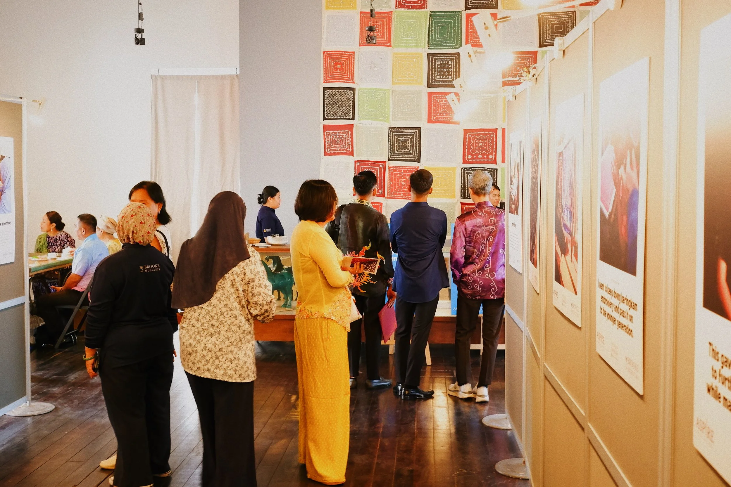 People viewing artwork and photographs in an art gallery or museum exhibition.
