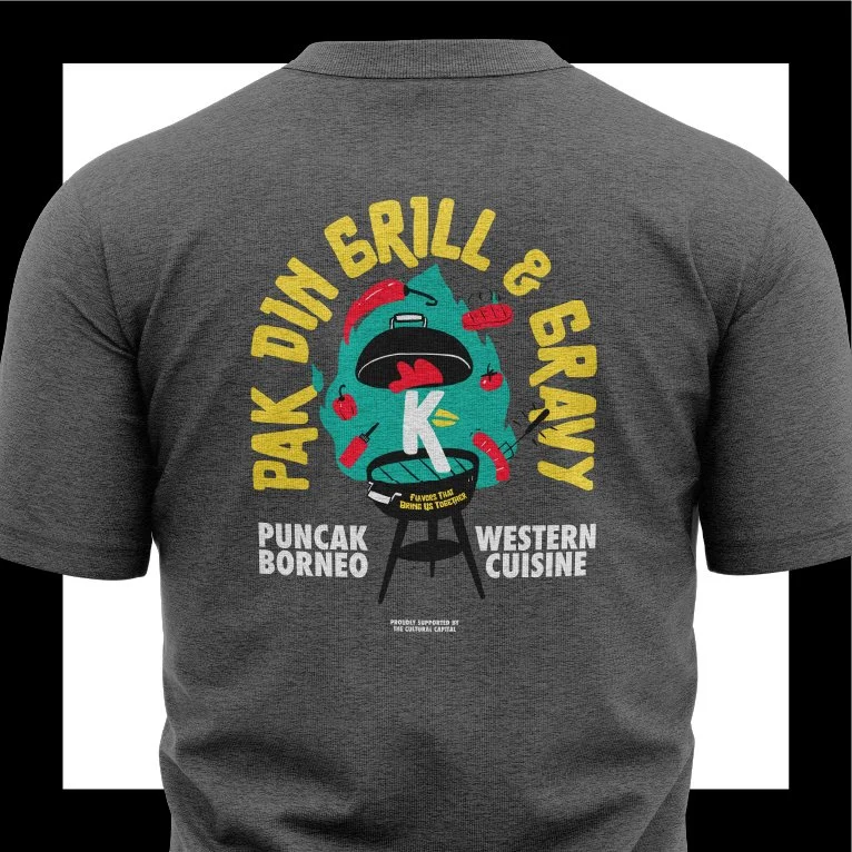 Back of a gray T-shirt with a graphic of a crying fish on a grill, surrounded by apples, fish, and cooking tools. Text reads 'Pak Din Grill & Gravy,' 'Puncak Borneo,' and 'Western Cuisine'.