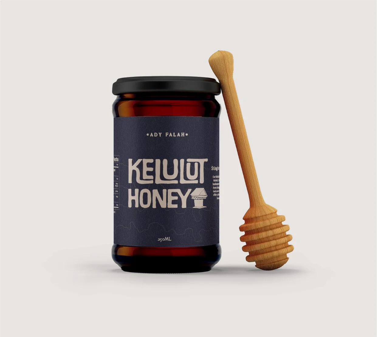A jar of Kelulut honey with a honey dipper hanging beside it on a plain background.