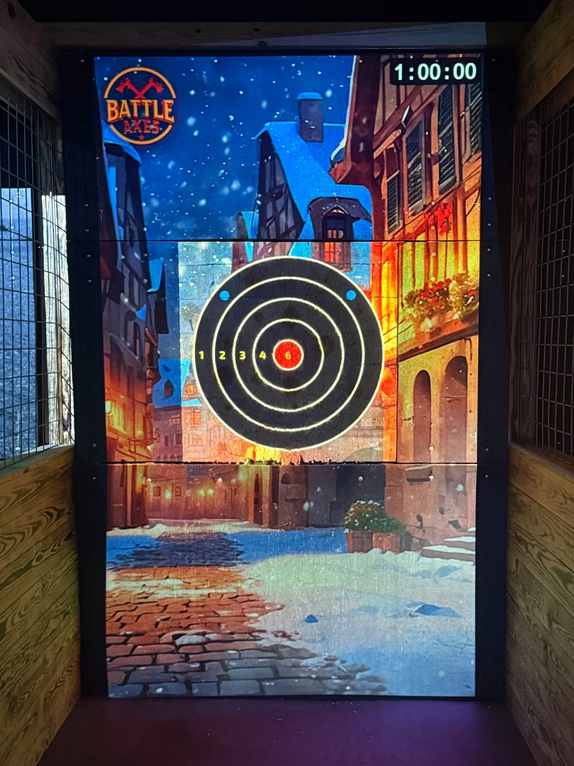 An indoor arcade game for shooting targets with a winter village scene background, branding labeled 'Battle Axes', and a timer at 1 minute.