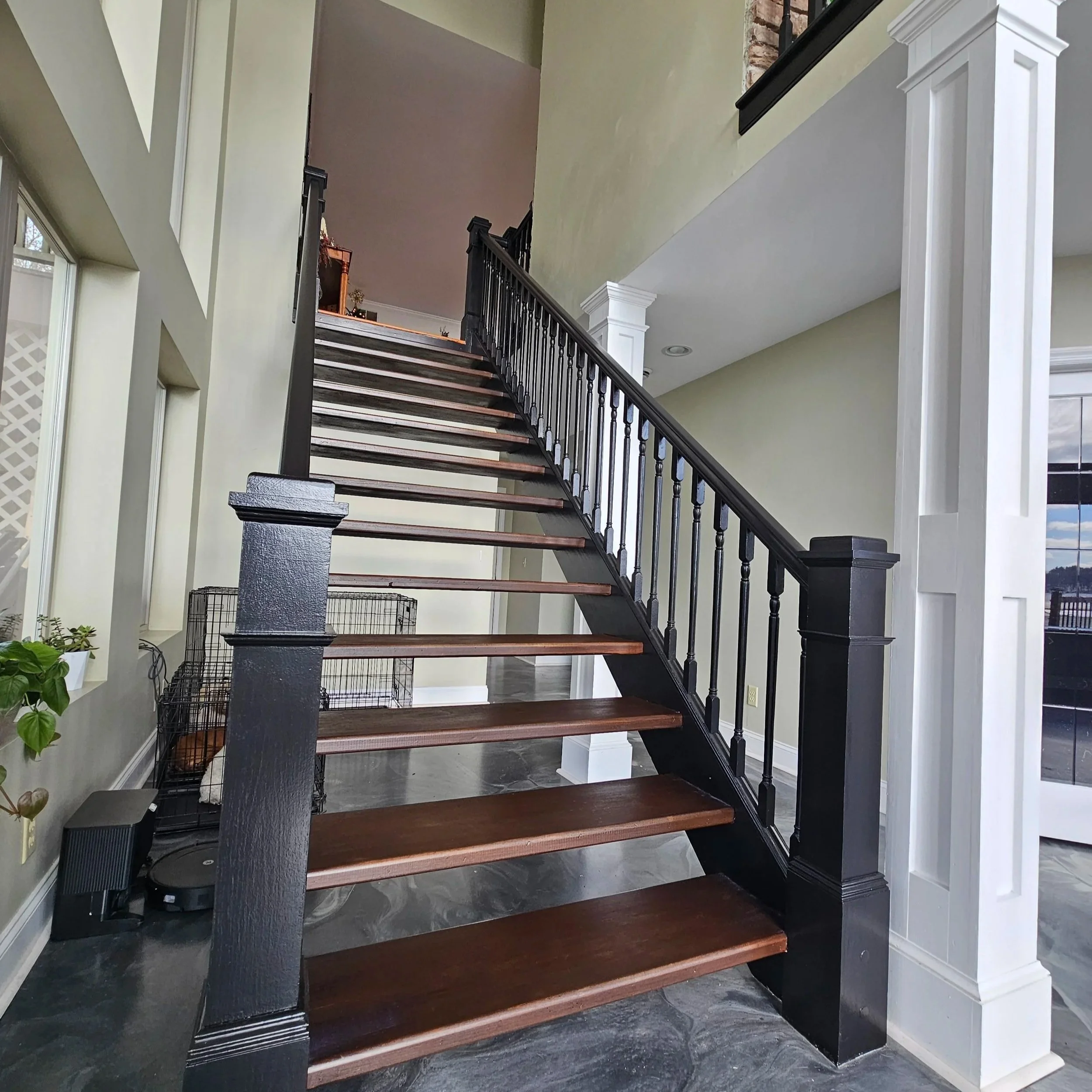 Interior view of a staircase with dark wooden steps, black and white railing, and light-colored walls. 