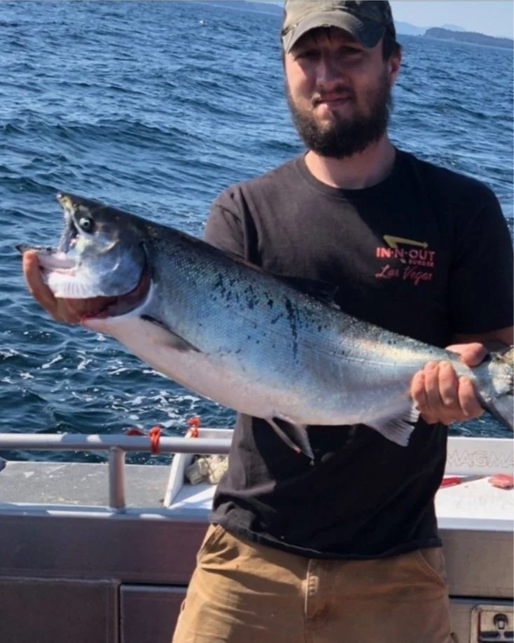 Captain holding a king salmon caught while trolling during a charter fishing trip in Kodiak, Alaska