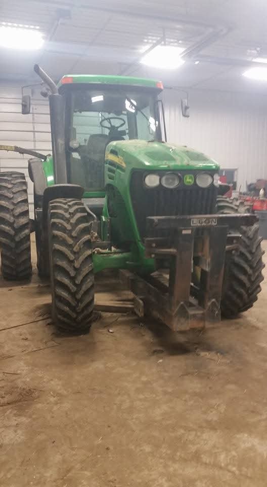 A green tractor with large tires inside a garage.