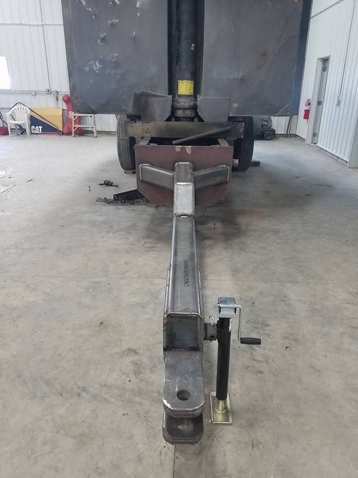 Large metal trailer hitch inside a garage with a jack stand.