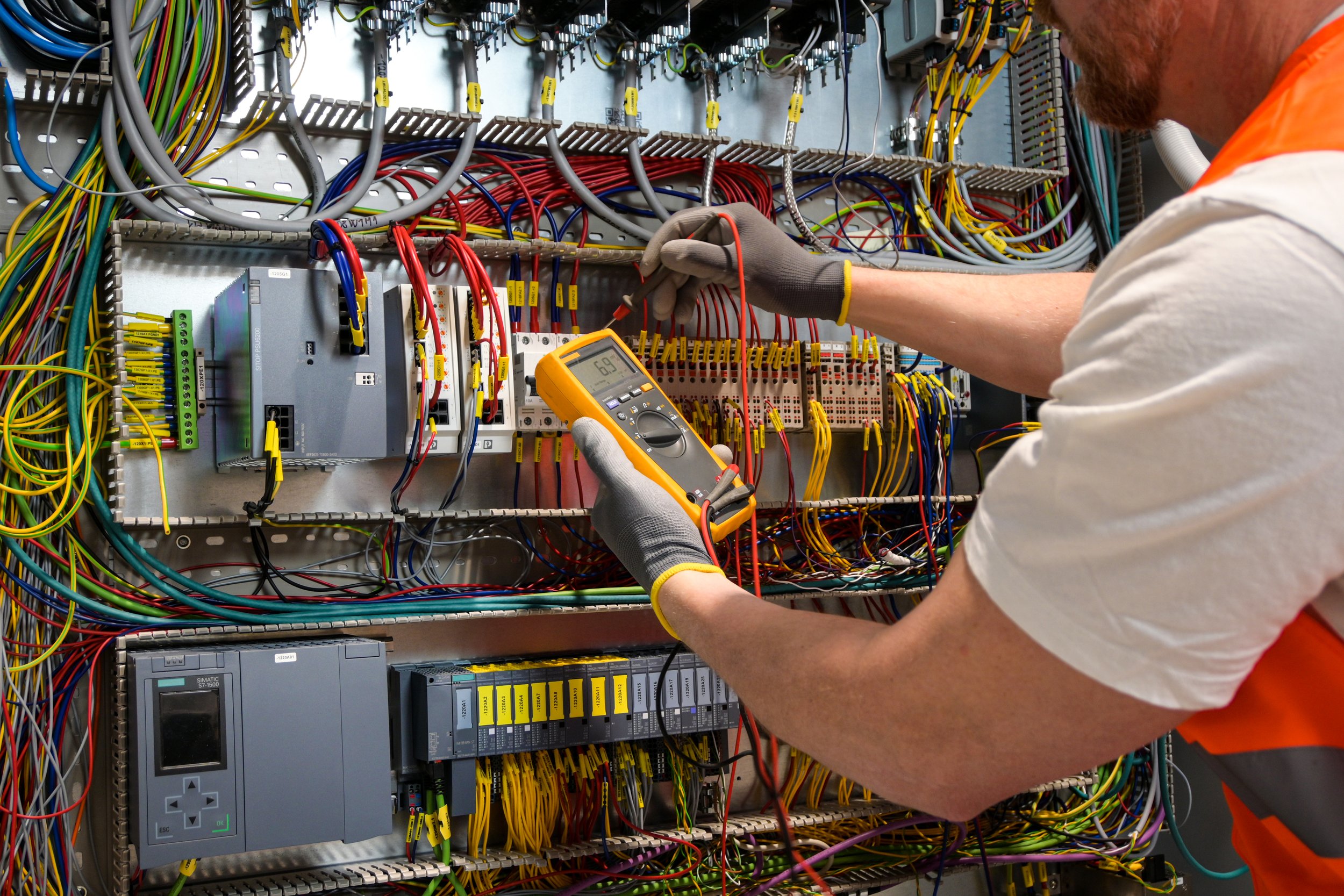 An electrician is performing testing on a switchboard
