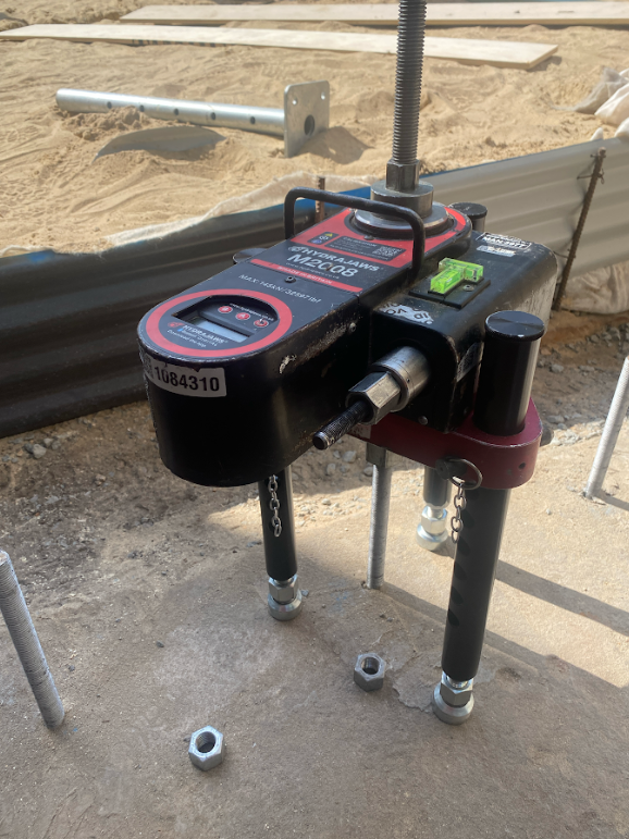 Hydrajaws M20 pull-out testing equipment verifying anchor capacity on outdoor infrastructure project.