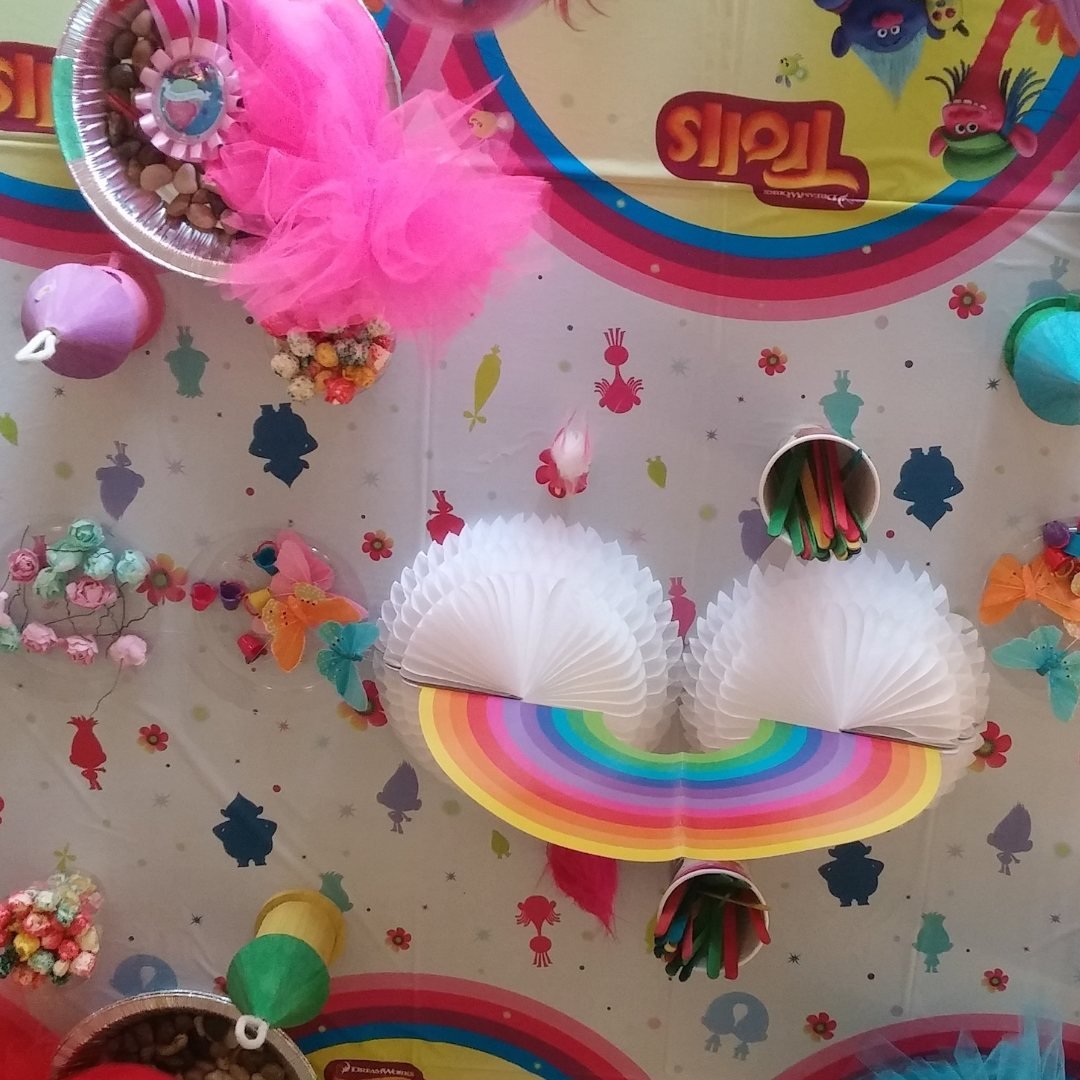 Colorful Trolls themed backdrop with various decorations like paper fans, rainbow patterns, and flowers.