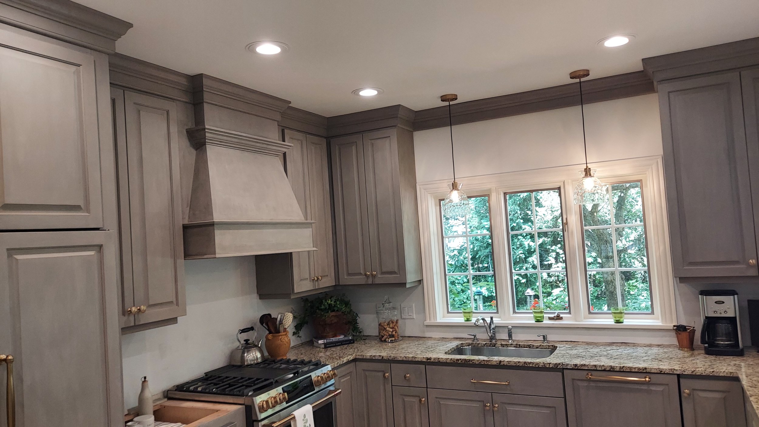 Kitchen with gray cabinets, granite countertops, a window above the sink, and pendant lights hanging from the ceiling.