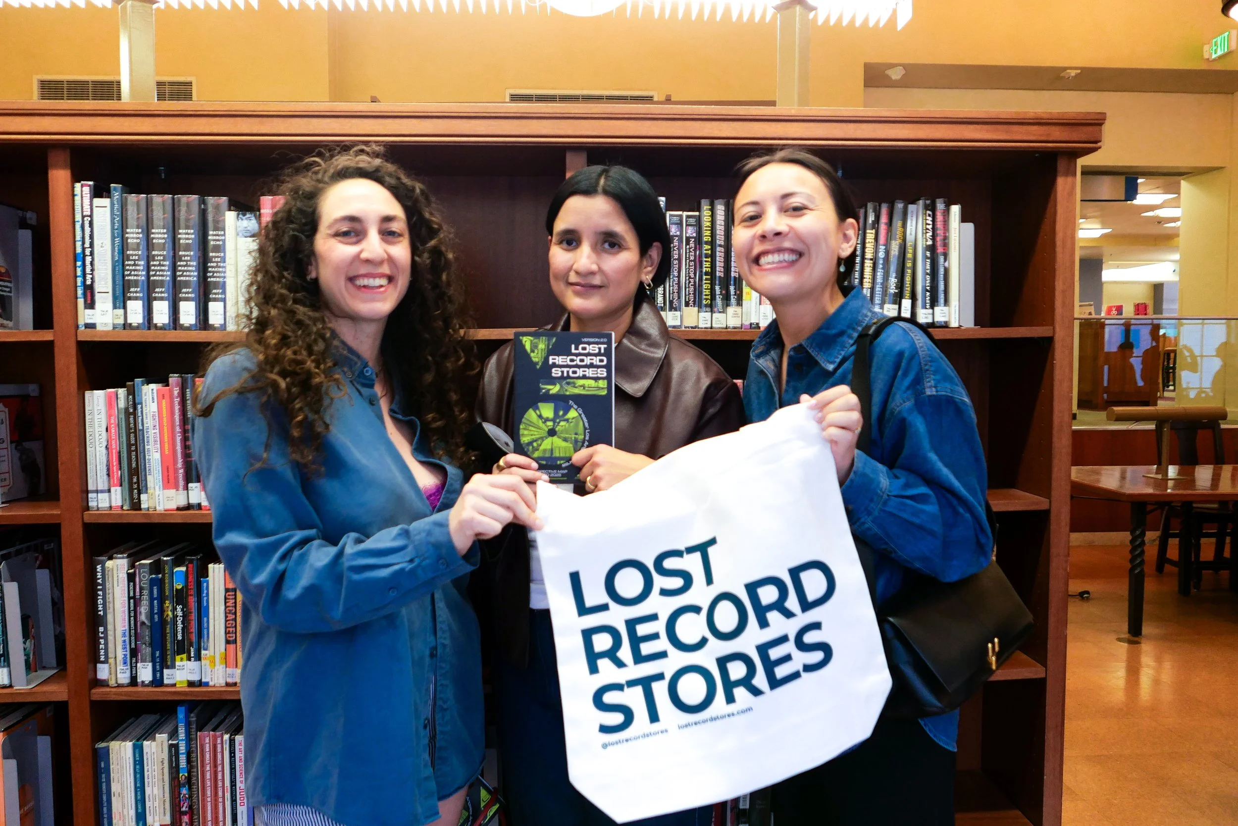 Three people with a Lost Record Stores Tote Bag an Map