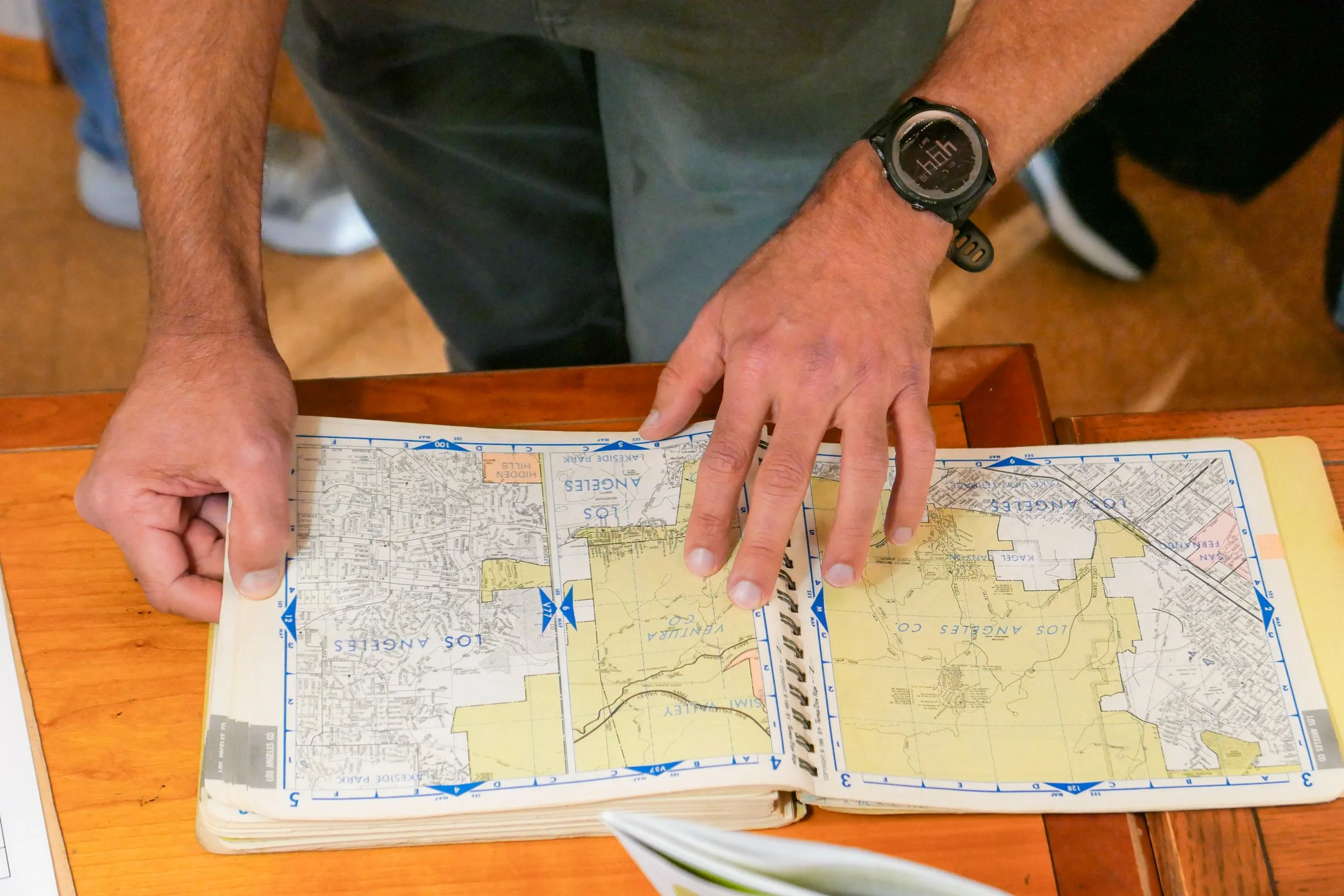 A person looking at a Thomas Guide map book