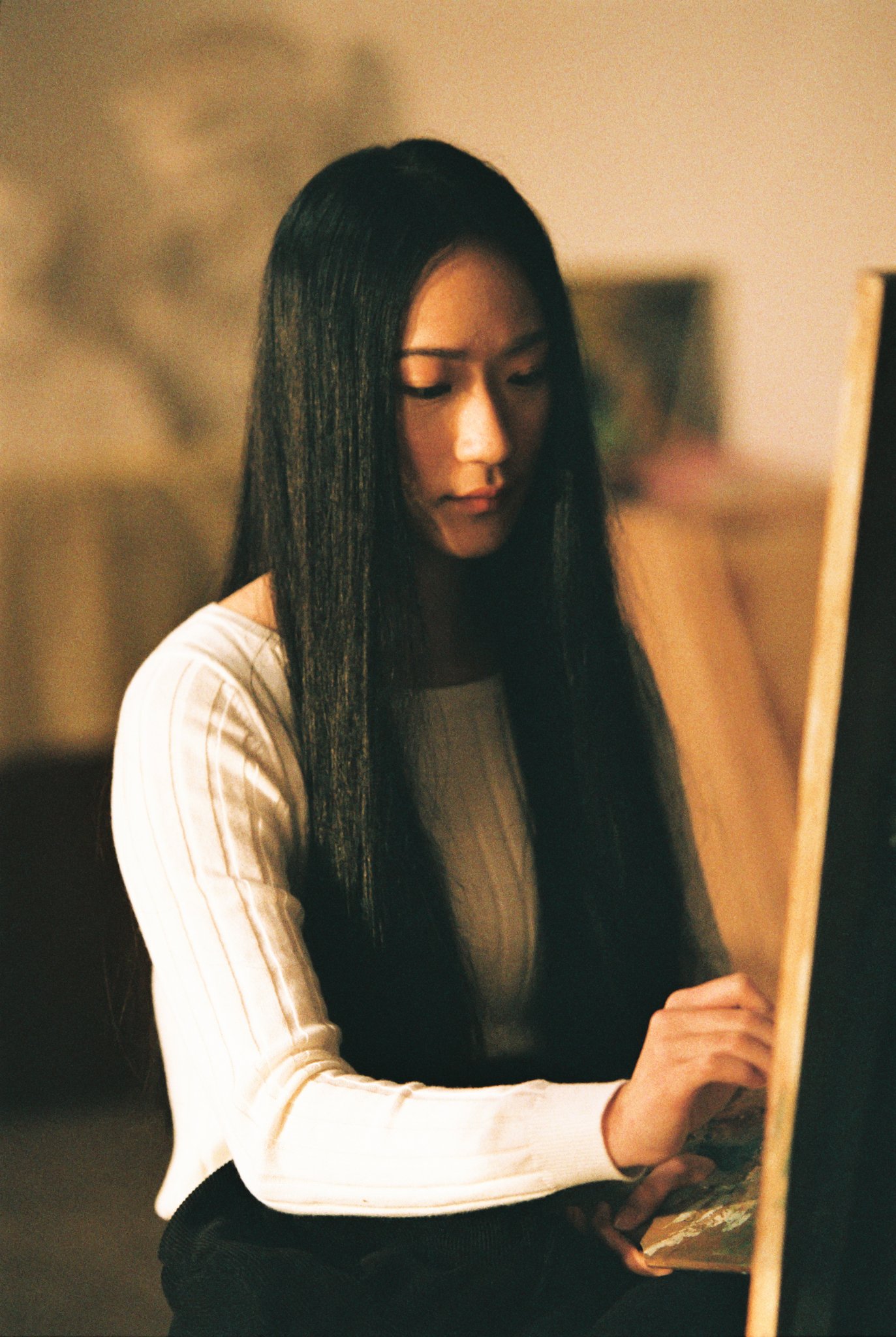 Woman with long hair painting on a canvas indoors