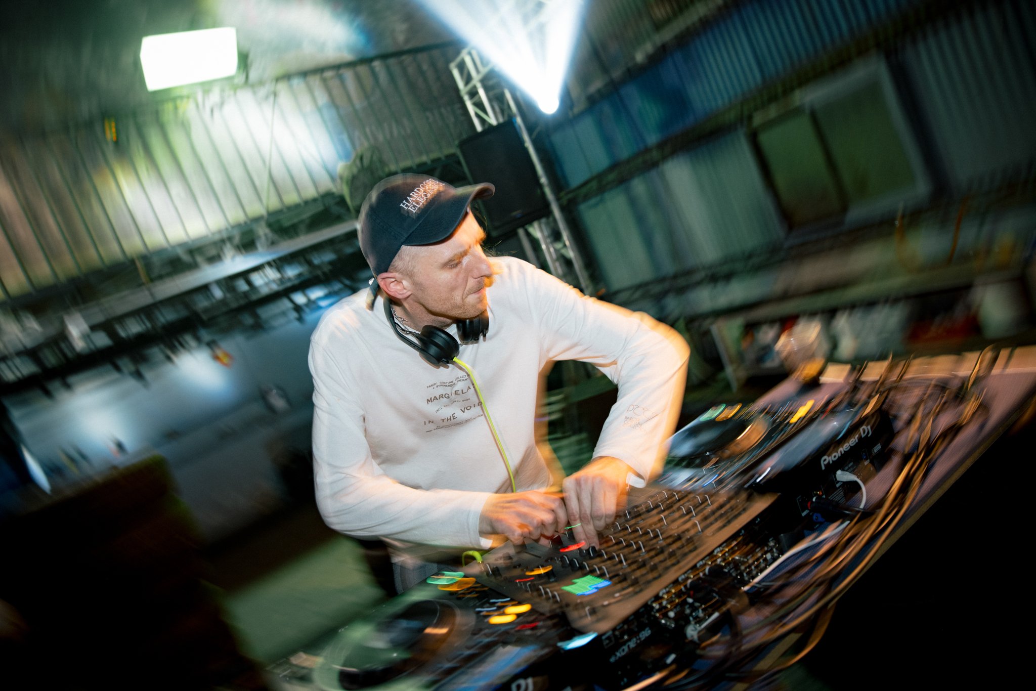 DJ performing with mixing equipment in a dimly lit venue