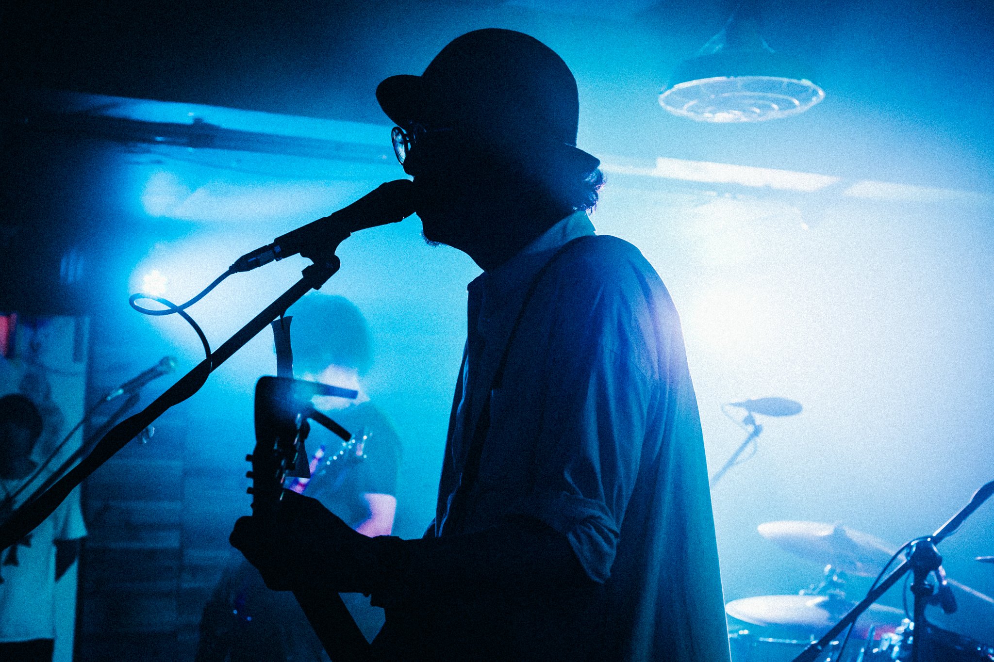 Silhouette of a musician on stage with a guitar and microphone, blue backlighting.