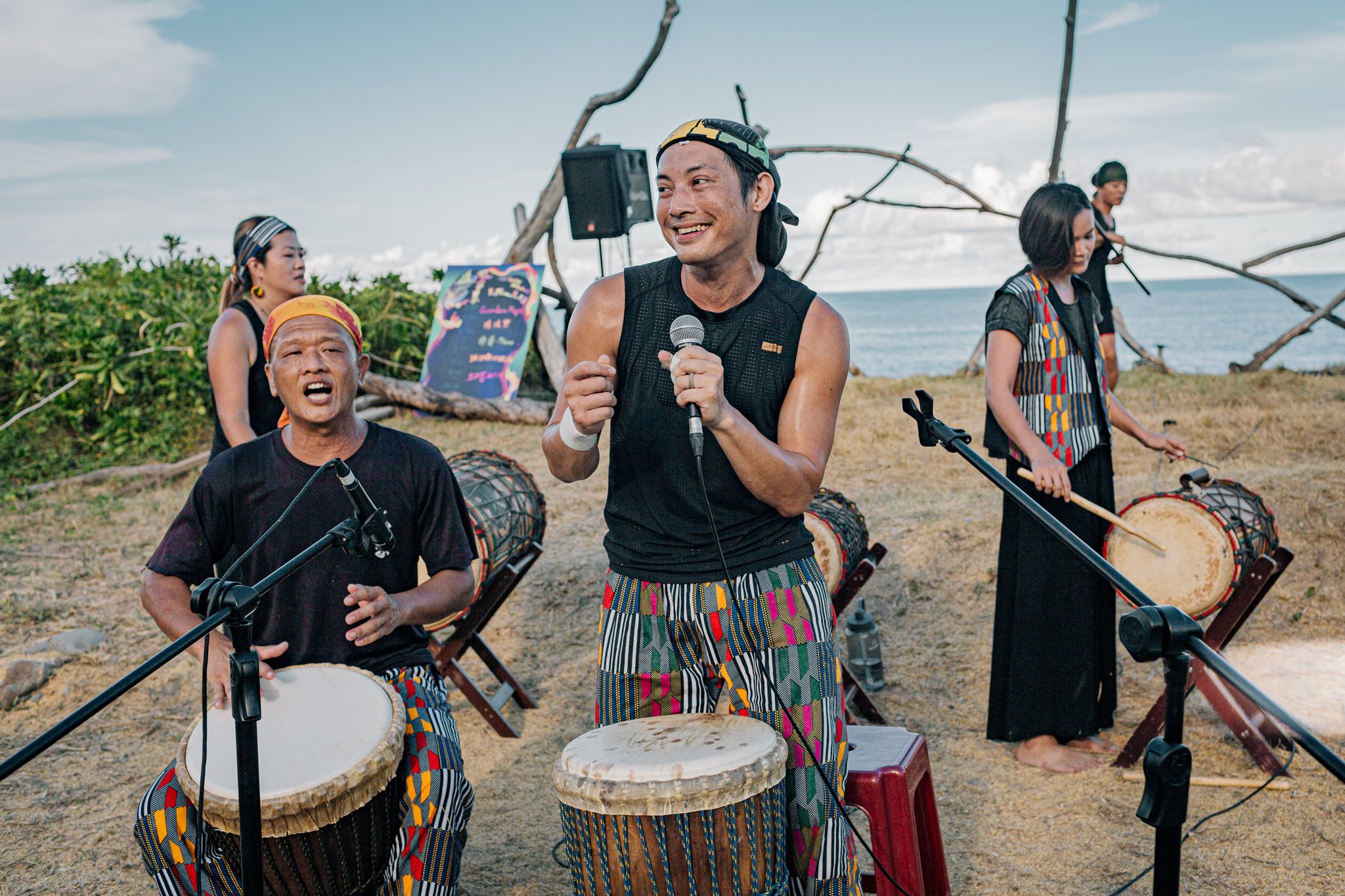Group of musicians playing traditional drums outside by the sea
