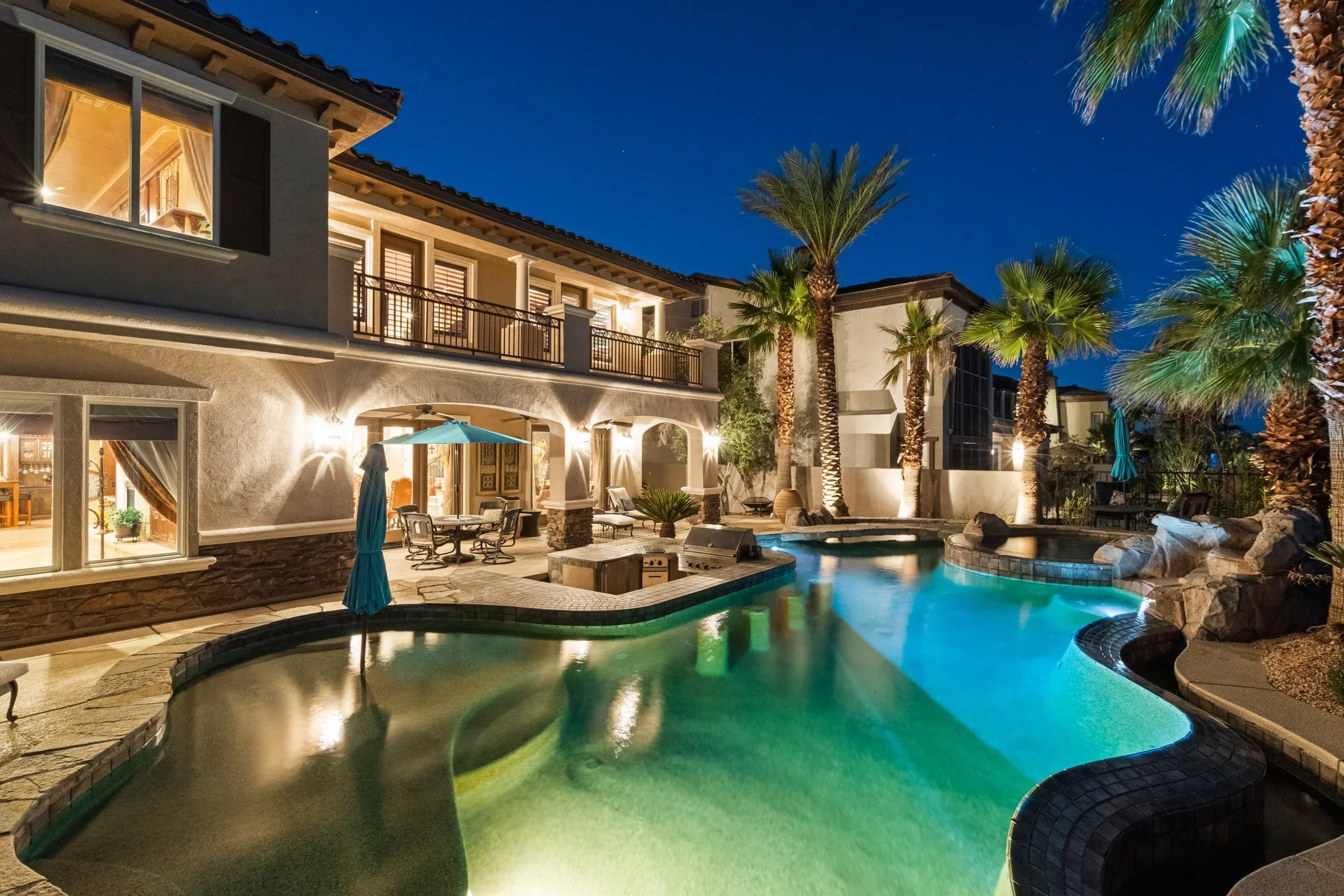 Twilight photography of a Beverly Hills backyard with a lit pool and palm trees.