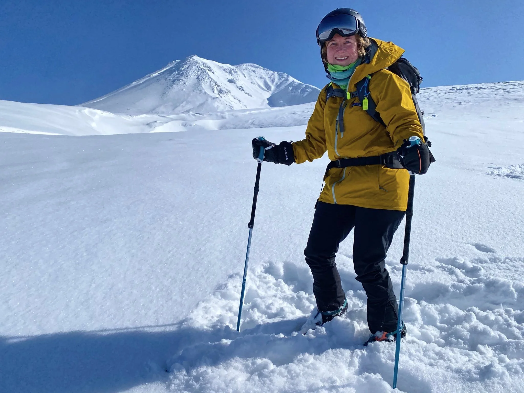 Person skiing in snowy mountain landscape with clear blue sky.