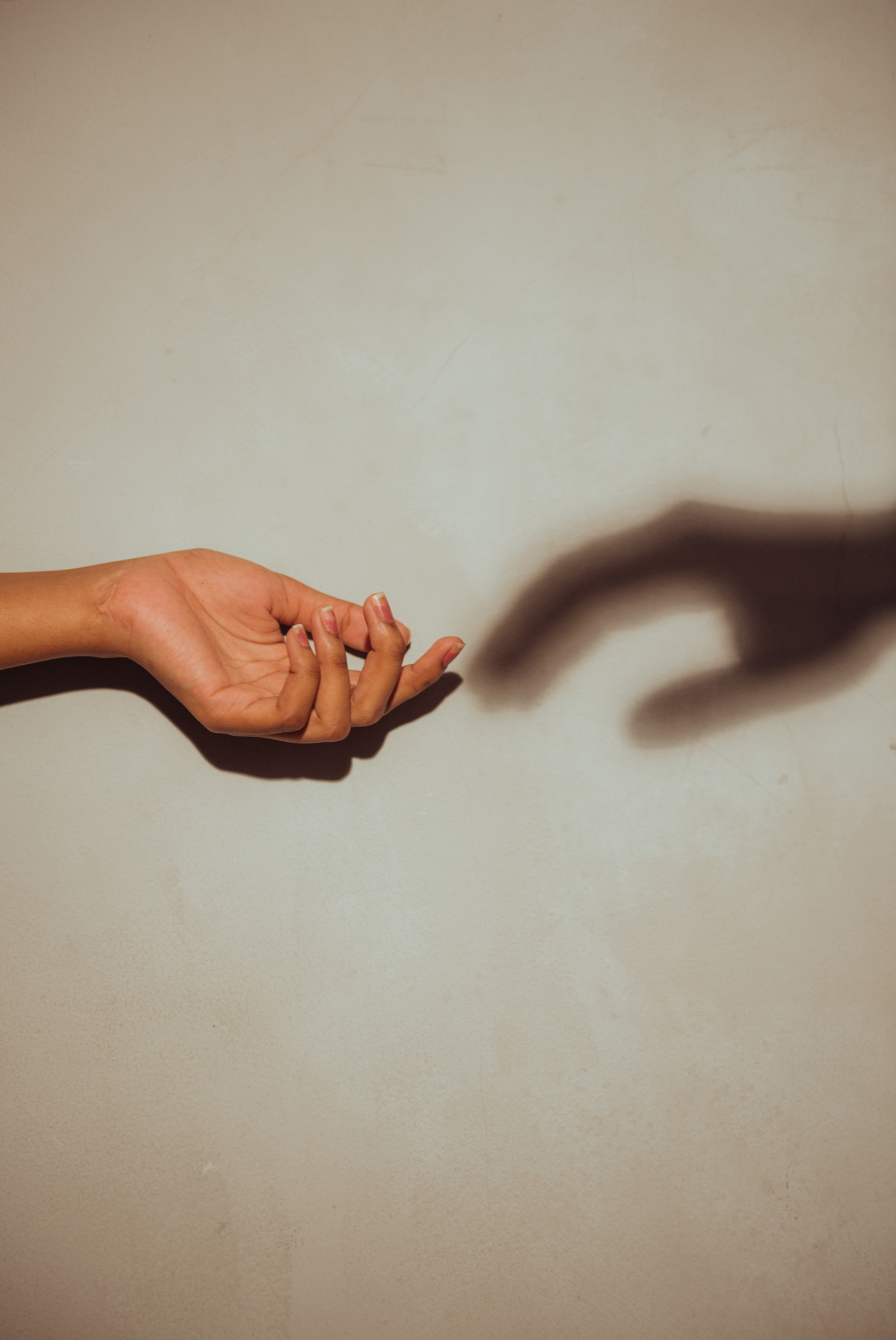 A hand reaching toward the shadow of another hand, representing connection.