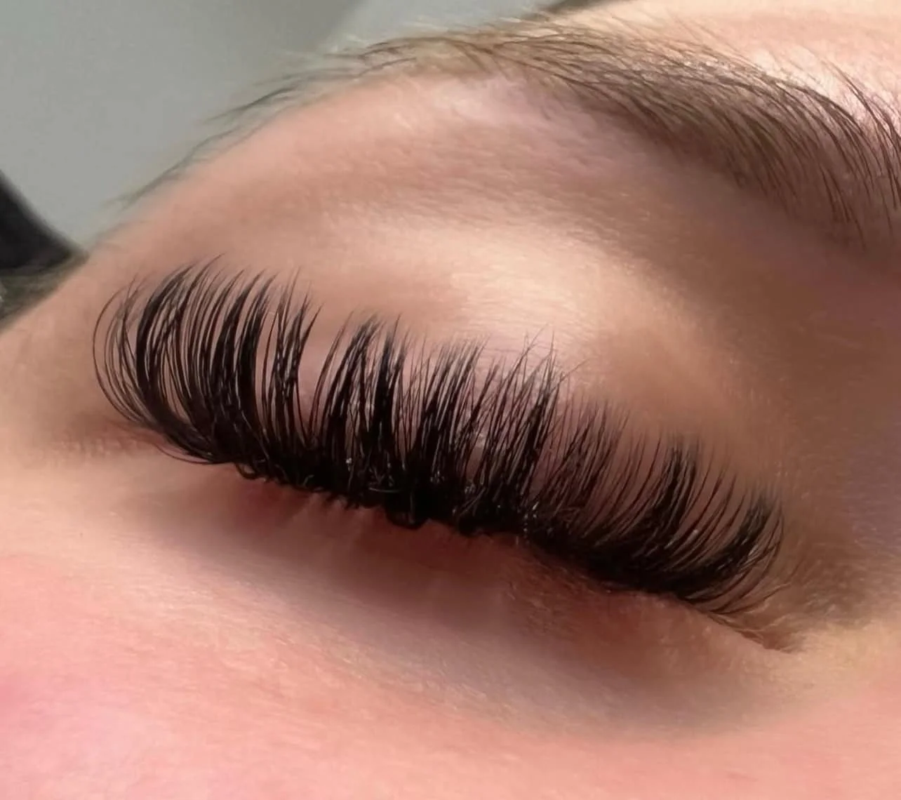 Close-up of a closed eye with long, thick eyelashes and well-groomed eyebrows.