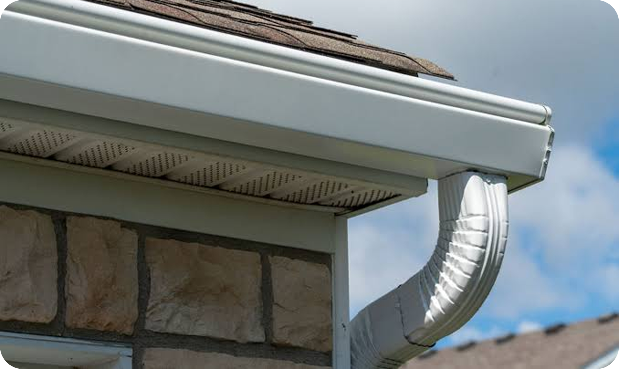 Close-up of a house gutter system with a blue sky background.