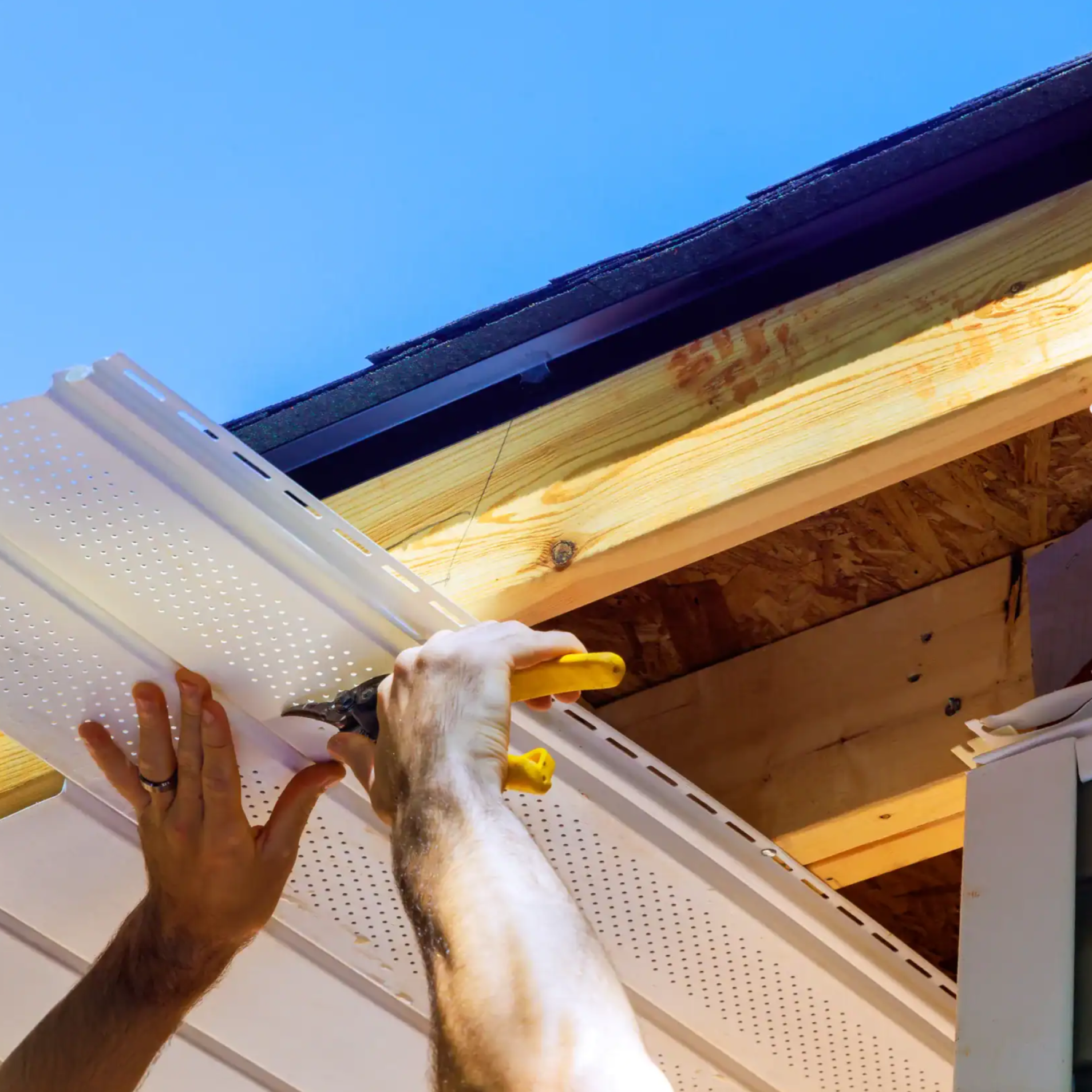Person using a yellow-handled tool to install or adjust a white perforated shelf bracket on a wooden shelf.