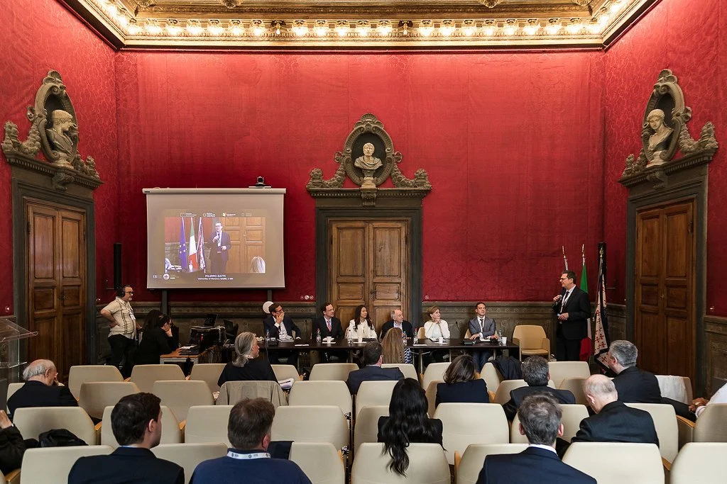 The Closing Roundtable “Charting the Course—Collaborative Strategies for the Future of Digital Money” in progress, with the projection screen and full speakers' table. Sala Rossa, Villa Ruspoli, 10 May 2025. Photo: Andrea Pecchioli / Fotoproject.