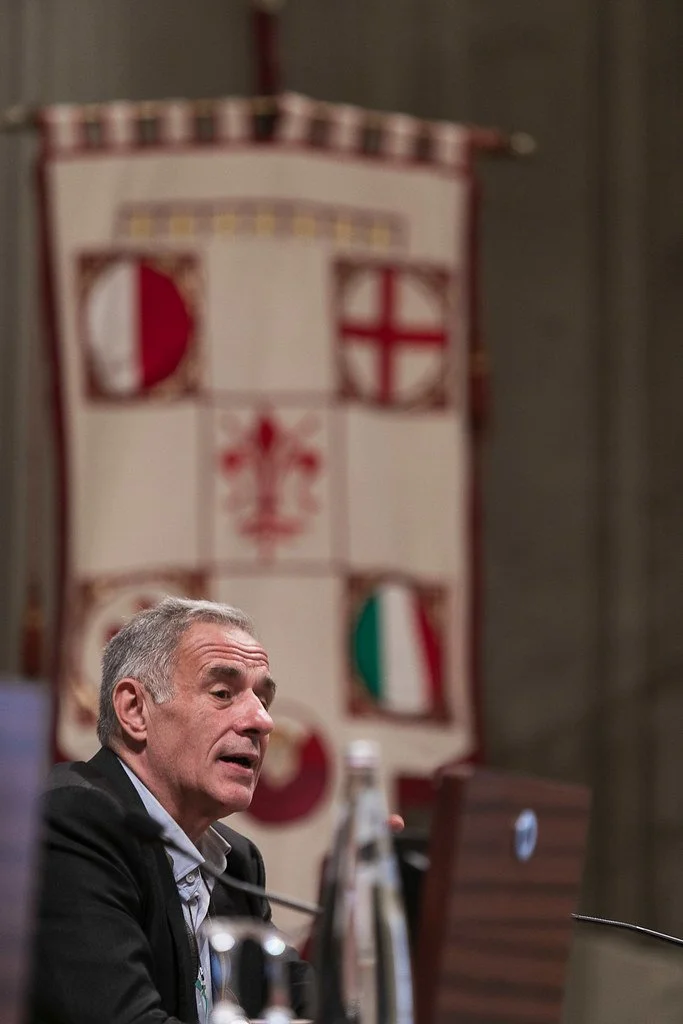 Christos Gortsos chairing the opening roundtable, with the historic gonfalone of Florence in the foreground. Aula Magna, Rector's Office Building, 8 May 2025. Photo: Andrea Pecchioli / Fotoproject.