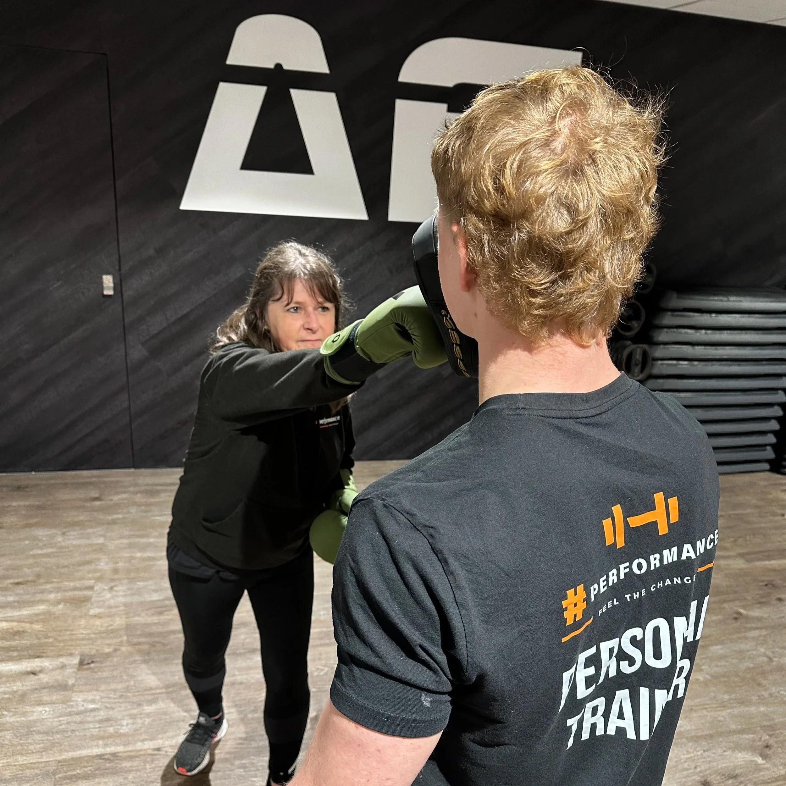 Woman punching a mitt during a personal training session at a fitness center.
