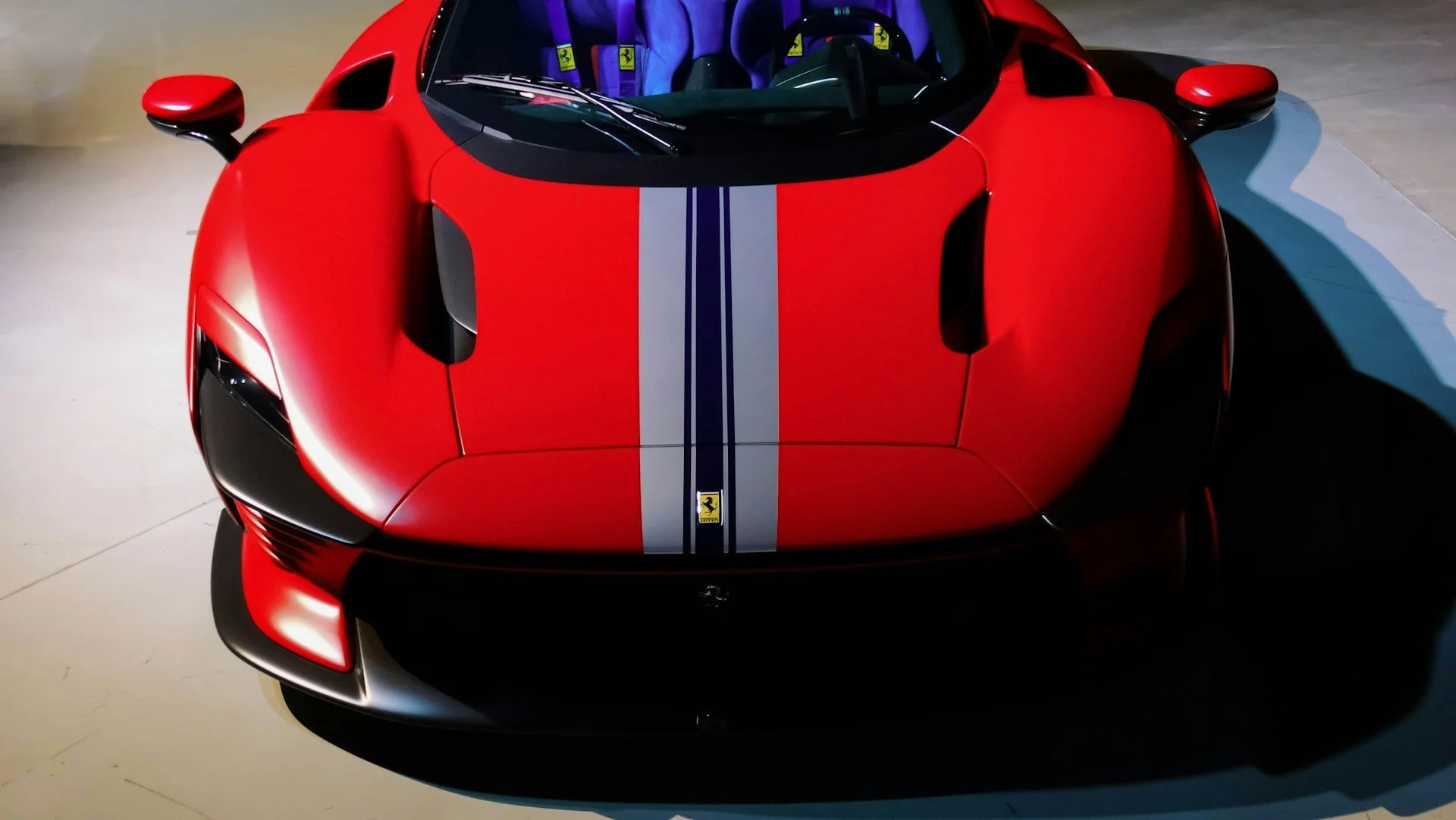 Ferrari Daytona SP3 von vorne in Rot mit Rennstreifen – Aufnahme im Showroom mit Fokus auf Karosserie und Luftführung