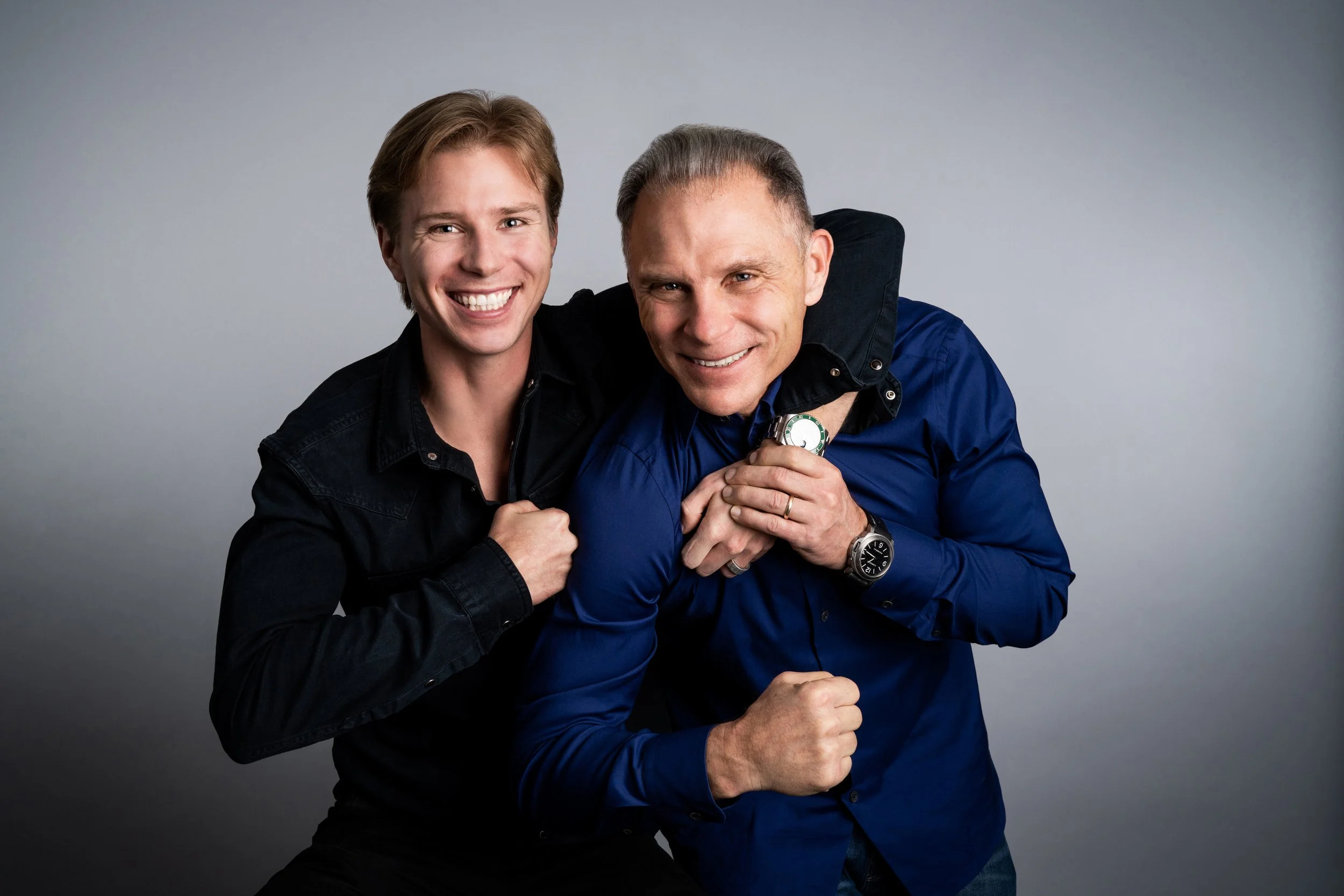 Porträtfoto von Kevin & Lukas Czinger, den Gründern von Czinger Vehicles. Vater und Sohn lachen in die Kamera und symbolisieren die familiäre Innovationskraft hinter der Hypercar Marke Czinger. Zusammen entwickelten sie den 3D gedruckten Czinger 21C