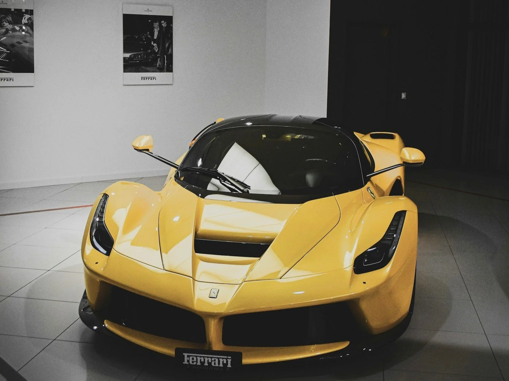 Frontansicht eines gelben Ferrari LaFerrari in einem Ausstellungsraum mit schwarzem Dach und aerodynamischem Design
