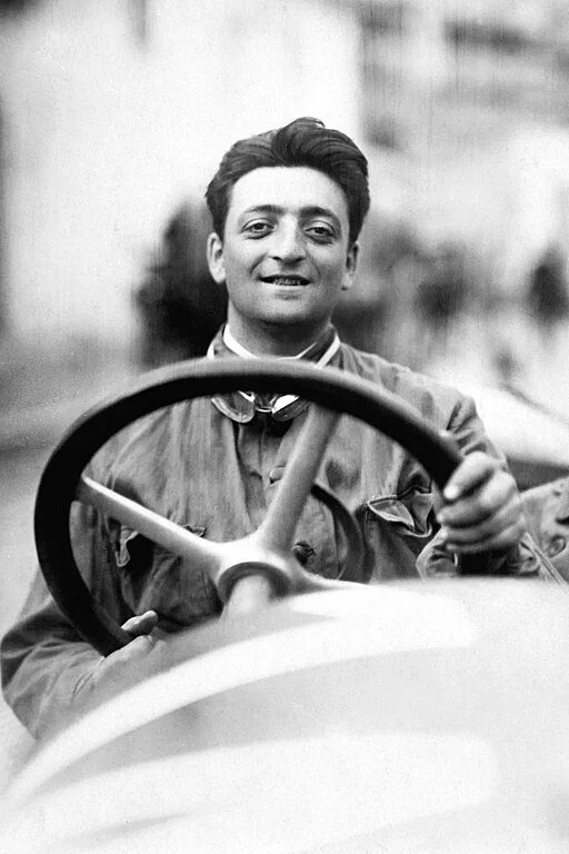 Junger Enzo Ferrari lächelnd am Steuer eines Rennwagens – frühe Aufnahme aus den 1910er-Jahren