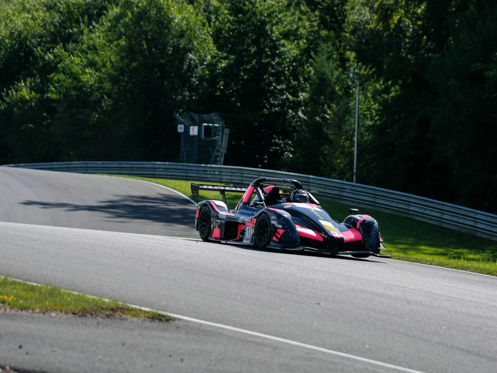 Ein Radical SR3 fährt mit hoher Geschwindigkeit durch eine Kurve auf einer abgesperrten Rennstrecke – exemplarisch für Trackdays, die ohne spezielle Zusatzversicherung ein erhebliches finanzielles Risiko für Hypercar-Besitzer darstellen.