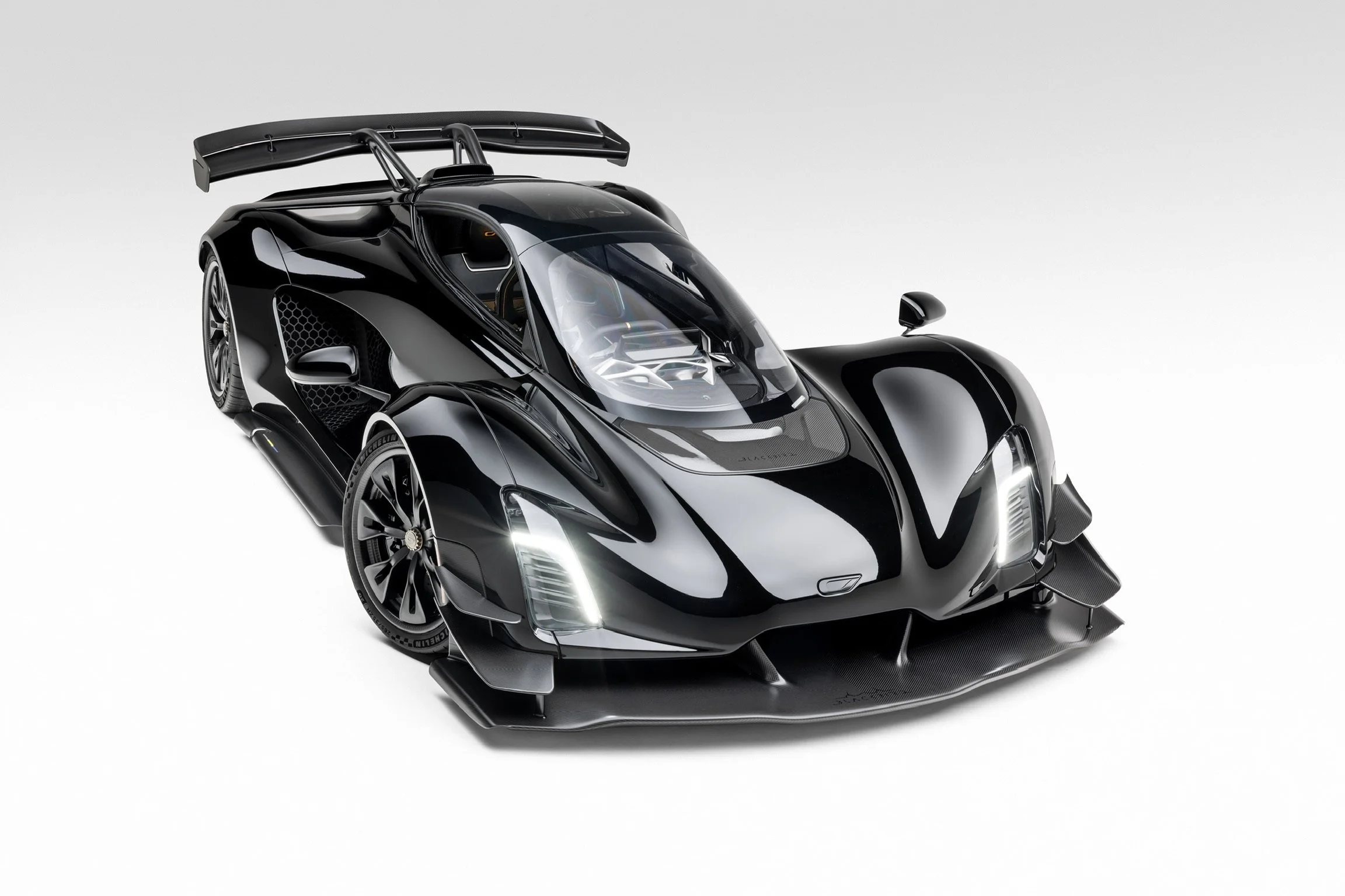 Czinger 21C in schwarzer Lackierung aus schräger Frontansicht mit großem Heckflügel, LED-Leuchten und sichtbarem Monocoque. Fokus auf Aerodynamik und Performance.