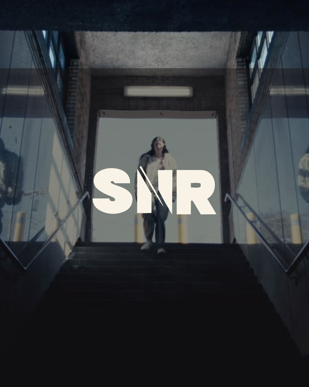 A person walking up stairs outside a building with large glass windows, with the words 'SINR' overlayed on the image.
