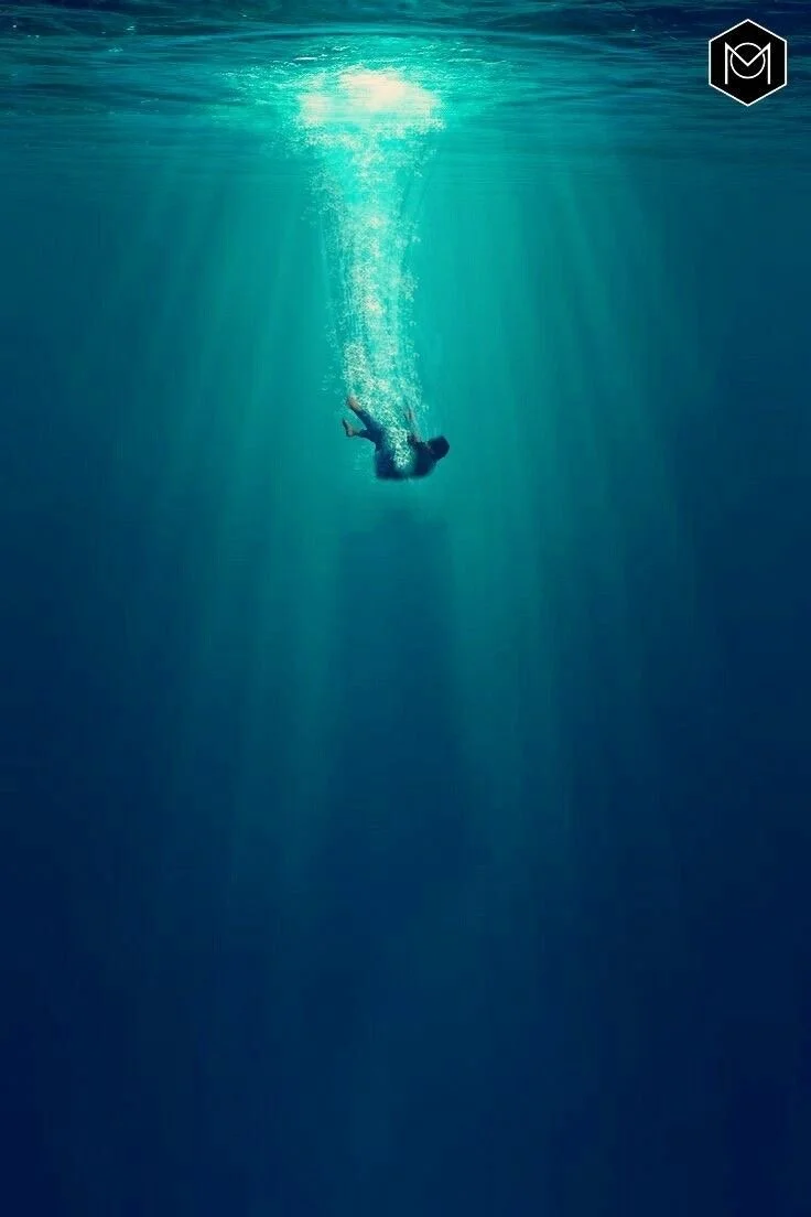 Personne nageant sous l'eau, avec des rayons de lumière traversant la surface.