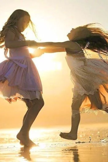Deux jeunes filles s'amusent sur la plage au coucher du soleil, se tenant par la main et sautant dans l'eau.