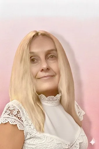 Une femme aux cheveux blonds lisses et longs, portant une blouse blanche avec des détails en dentelle, souriant légèrement, avec un fond rose clair.