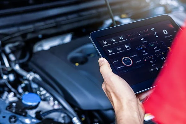 Persona utilizando una tableta para diagnosticar un motor de automóvil.