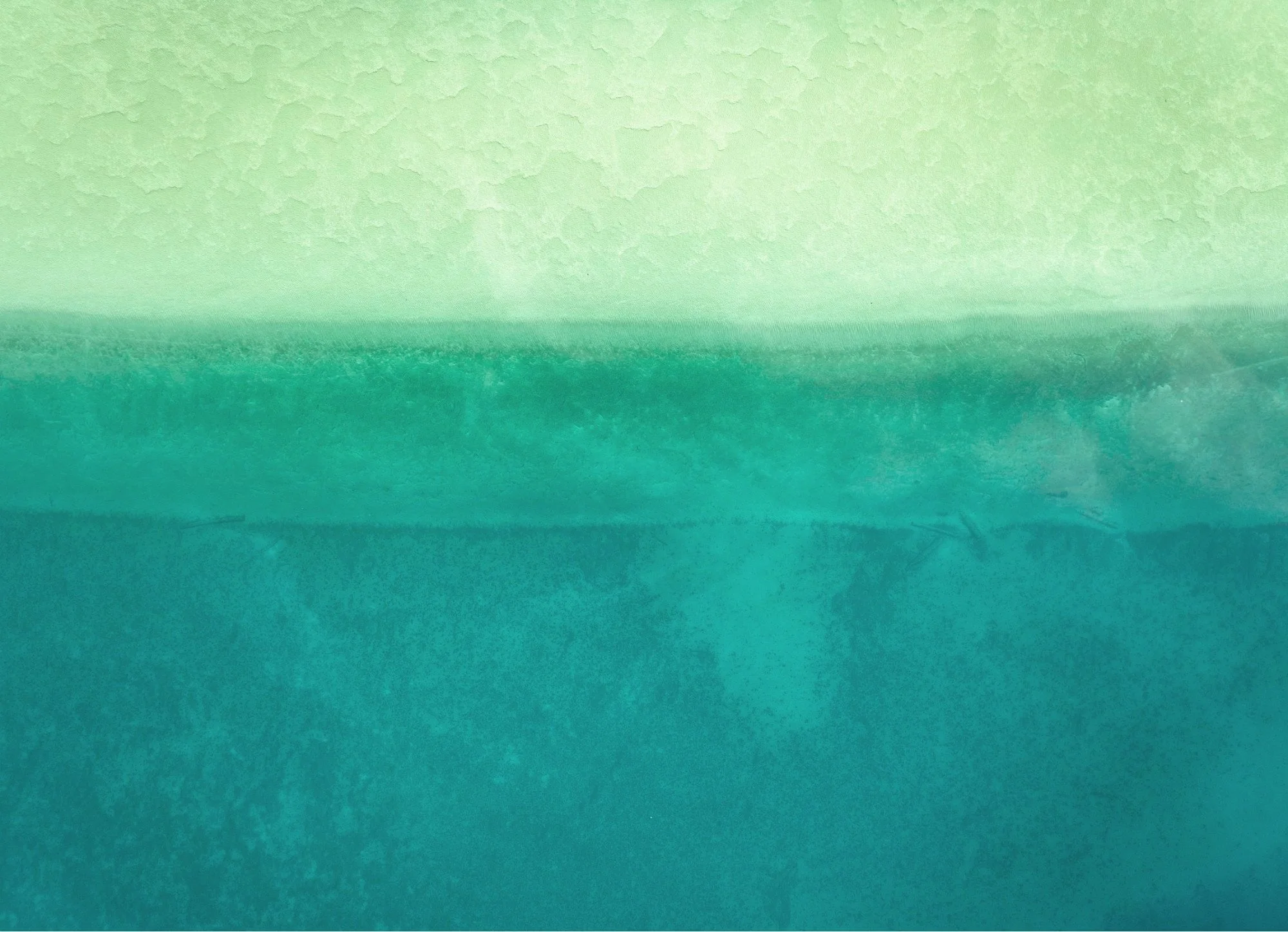Abstract aerial view of green and blue waters over Torch Lake with visible waves and textures taken with a drone in Northern Michigan.