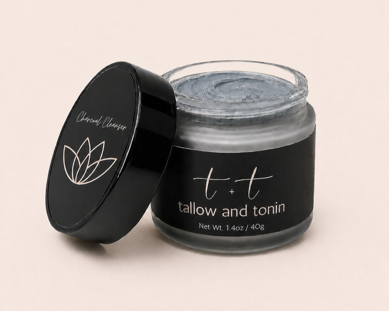 Open jar of skincare cream labeled 't + t tallow and tonin', with black lid beside on light background.