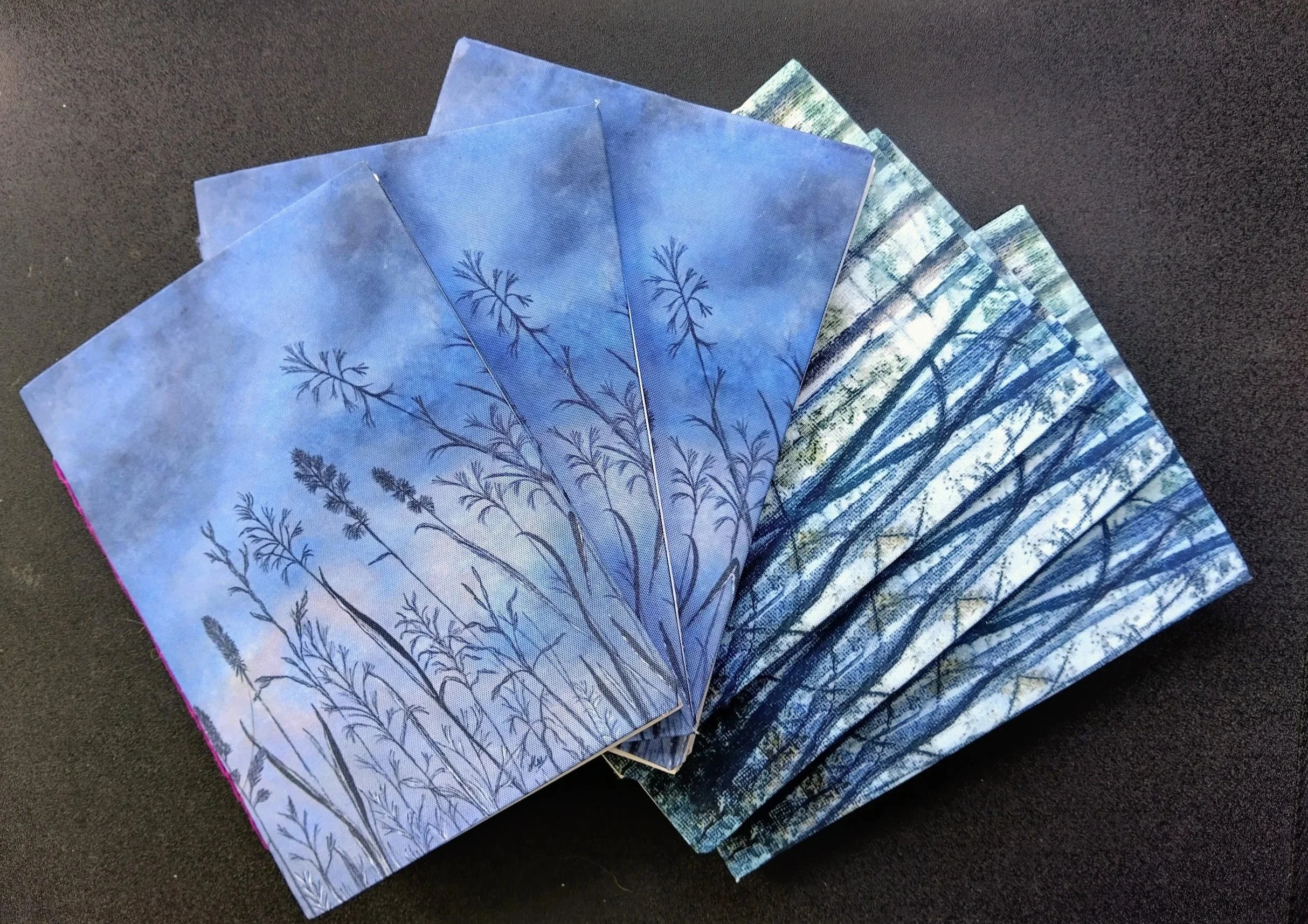 Five handmade softcover notebooks with two different cover designs, one in blue and one in green
