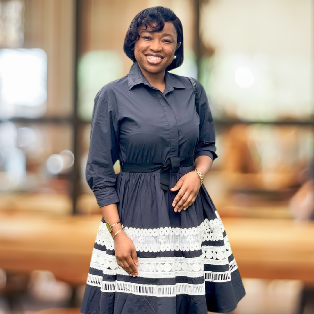 Woman smiling in a black and white patterned dress with a blurred background.