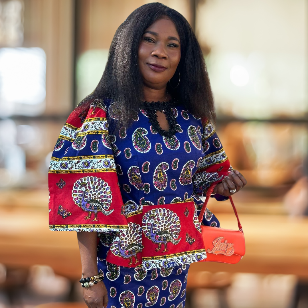 Woman in colorful traditional dress holding a red purse indoors.