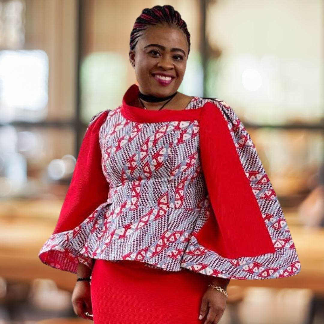 Woman in a red and patterned dress, smiling indoors.