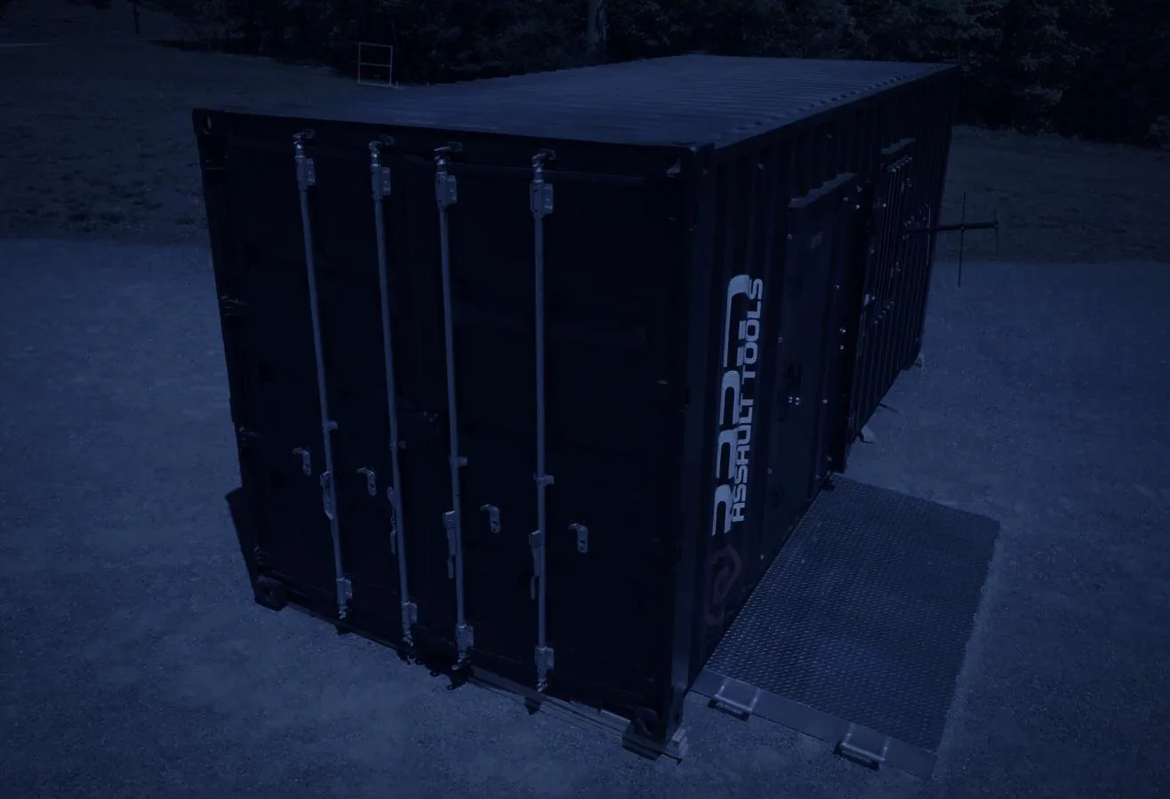 Rapid Assault Tools shoot by CXIX: a large, dark-colored shipping container with the logo 'R2B' on the side, positioned on a gravel surface at night.