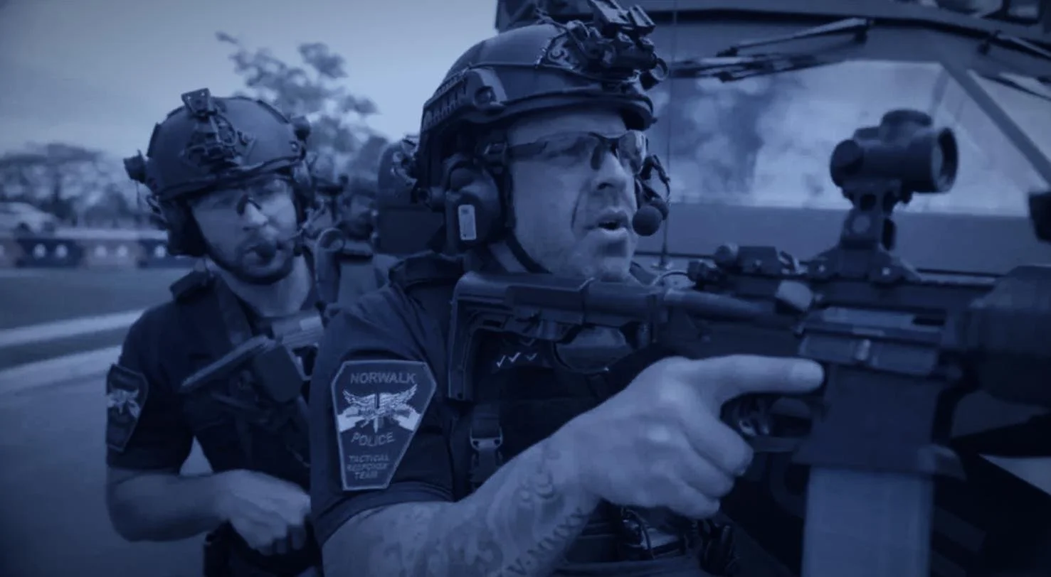 Long Island SWAT Challenge, shot by CXIX: two police officers in tactical gear, one aiming a rifle, during a night operation.